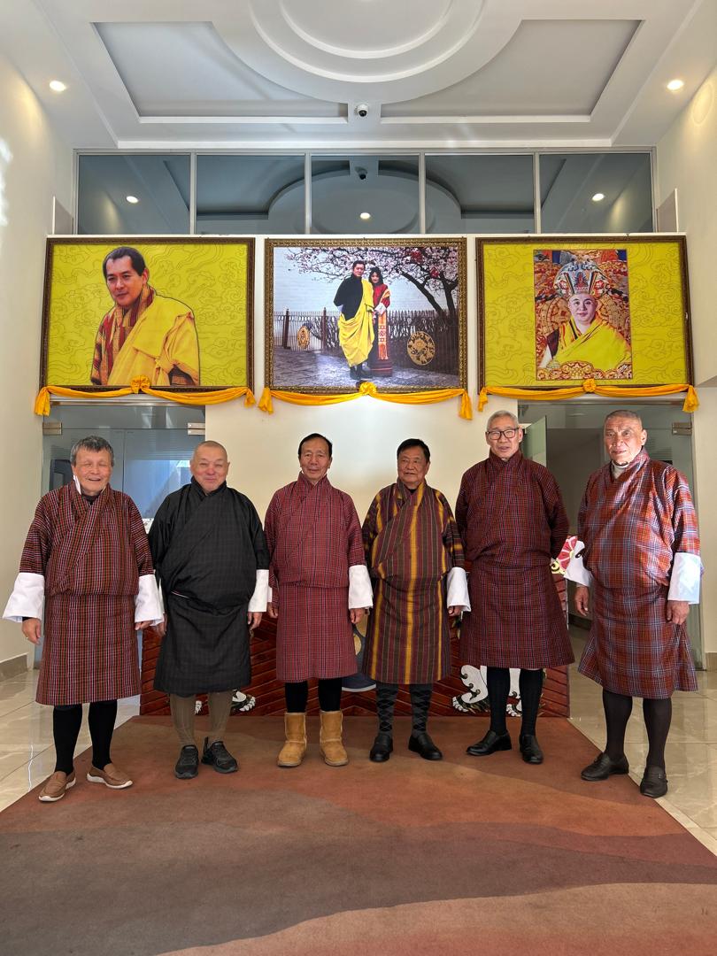 NGT members gathered together below portraits of Their Majesties.